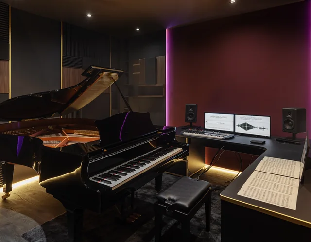 Grand piano and composition desk in a warmly lit studio